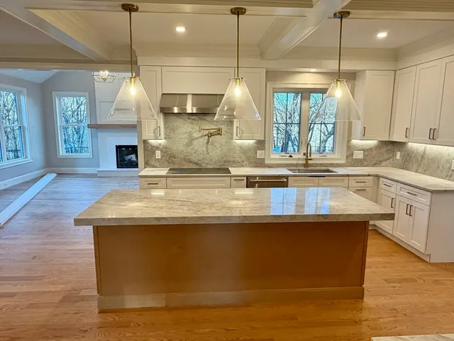 a kitchen with kitchen island granite countertop a sink a counter space appliances and a window