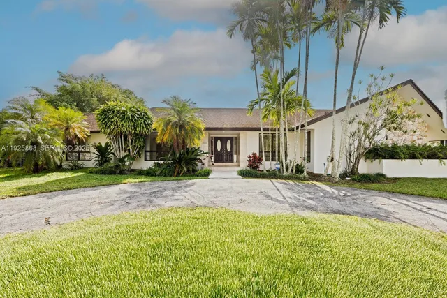 a view of a house with palm trees and a small yard