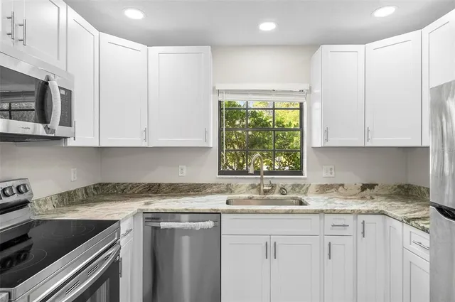 a kitchen with stainless steel appliances granite countertop white cabinets sink and granite counter tops