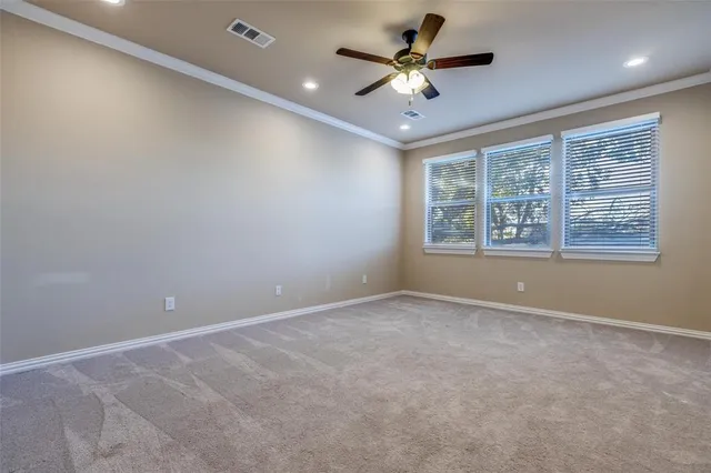 an empty room with a ceiling fan and windows