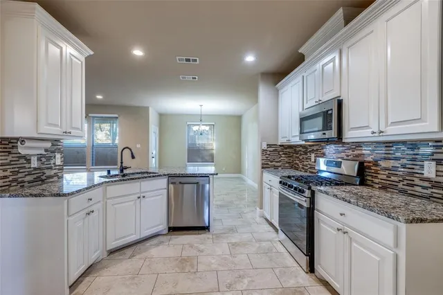 a kitchen with stainless steel appliances granite countertop a stove sink and cabinets