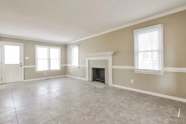 an empty room with windows and fireplace