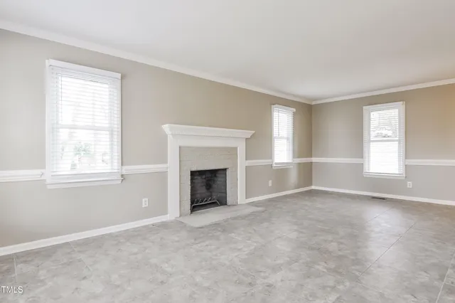 an empty room with windows and fireplace