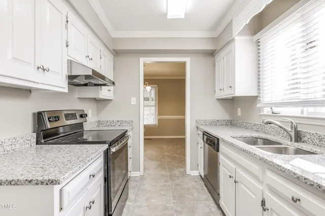 a kitchen with granite countertop a sink stove and cabinets