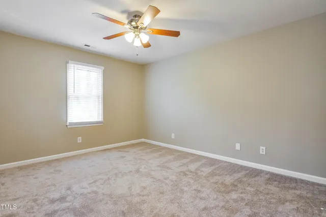 an empty room with windows and chandelier fan