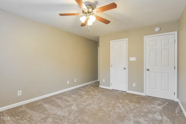 an empty room with closet and a chandelier fan