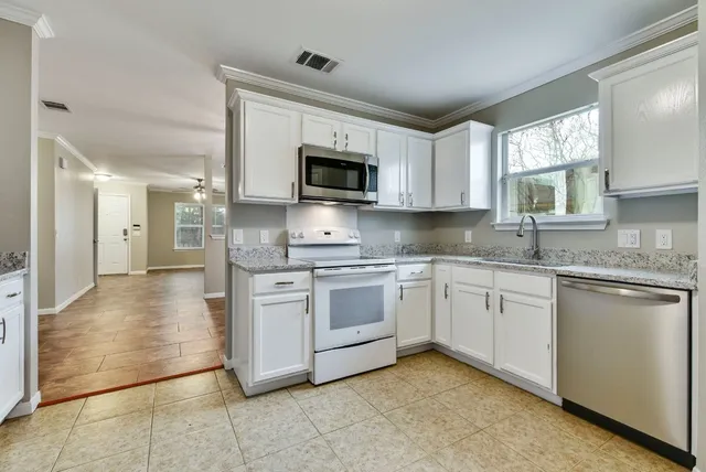 a kitchen with stainless steel appliances granite countertop a stove a sink and a microwave