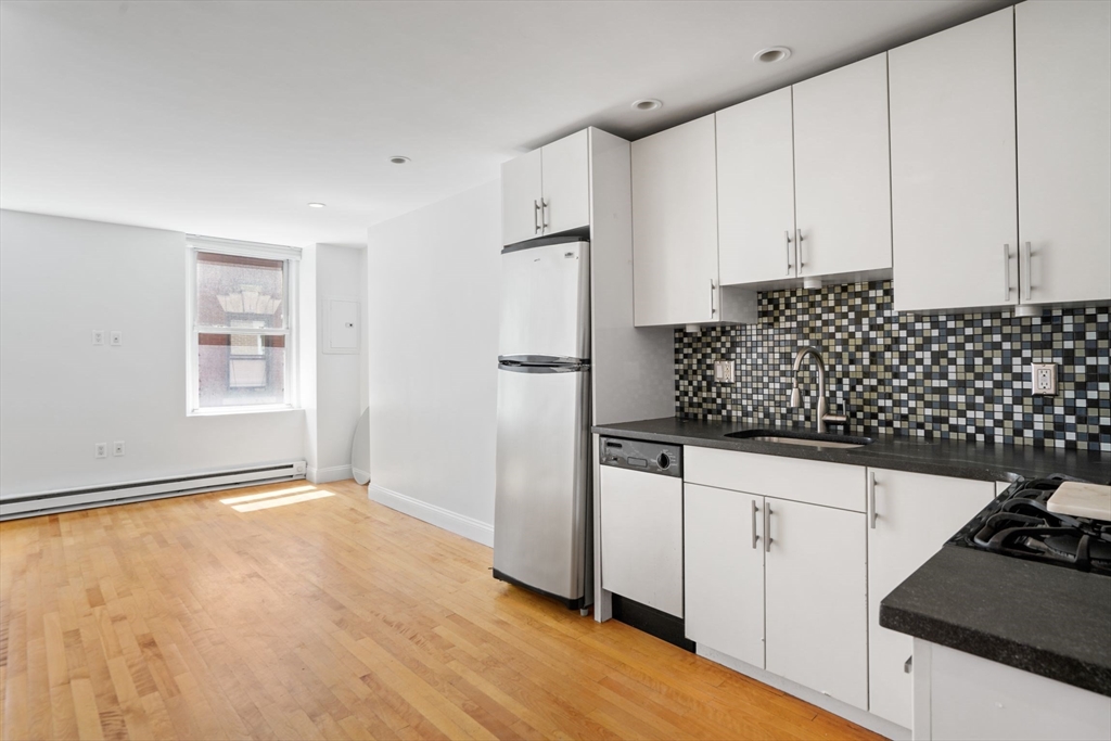 1 Unity Street, Unit 2F Boston, MA 02113 - Photo 2 of 16 a kitchen with granite countertop white cabinets and black appliances