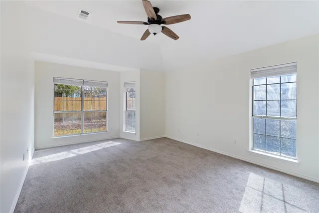an empty room with windows and fan