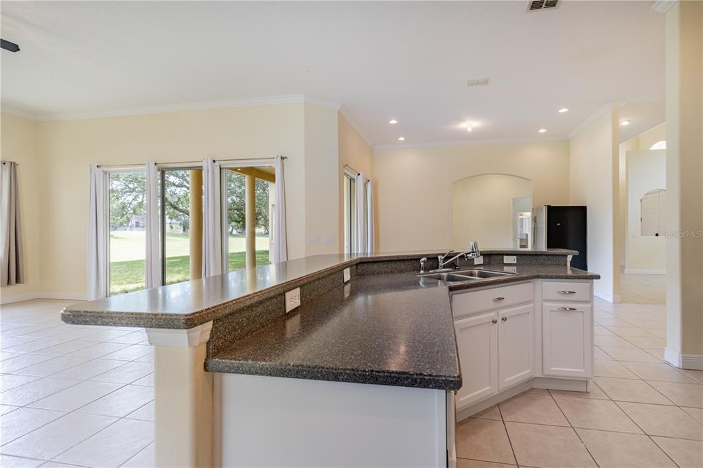 2718 Knightsbridge Road Clermont, FL 34711 - Photo 22 of 72 a large kitchen with granite countertop a sink and a stove top oven with wooden floor