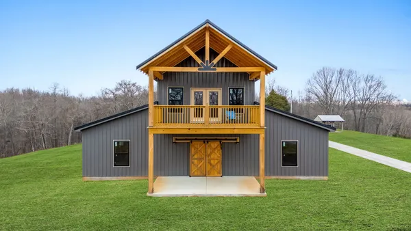 a front view of house with yard and trees in the background