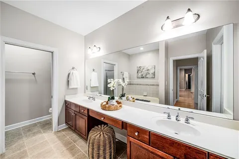 a spacious bathroom with a double vanity sink a mirror a bathtub and shower