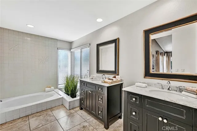 a spacious bathroom with a double vanity sink a large mirror and a bathtub