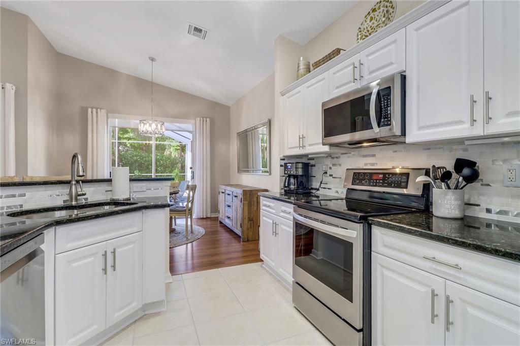 9146 Springview Loop Estero, FL 33928 - Photo 11 of 49 a kitchen with stainless steel appliances granite countertop white cabinets a sink a stove a microwave and a refrigerator