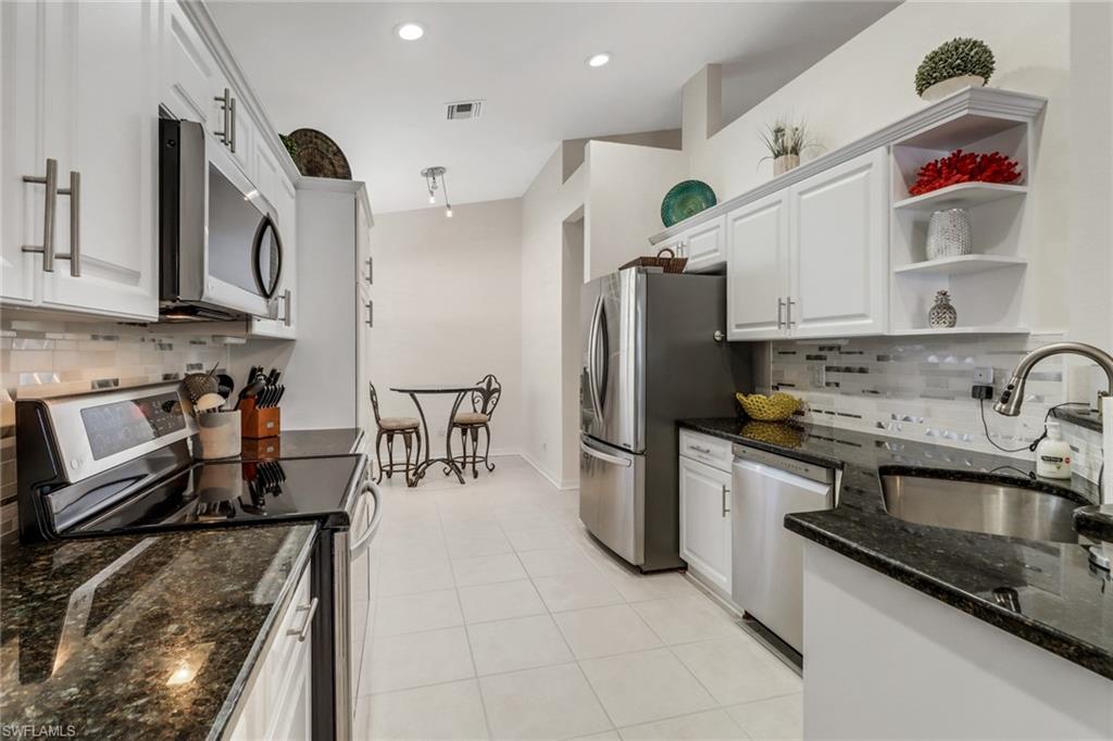 9146 Springview Loop Estero, FL 33928 - Photo 12 of 49 a kitchen with stainless steel appliances granite countertop a sink a stove and a refrigerator
