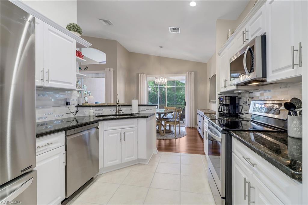 9146 Springview Loop Estero, FL 33928 - Photo 10 of 49 a kitchen with stainless steel appliances granite countertop a sink stove microwave and cabinets
