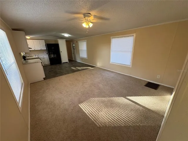 a view of kitchen and empty room with wooden floor