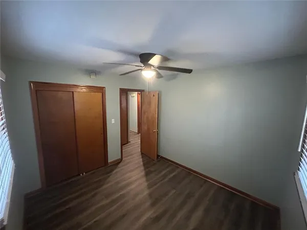 an empty room with wooden floor and fan