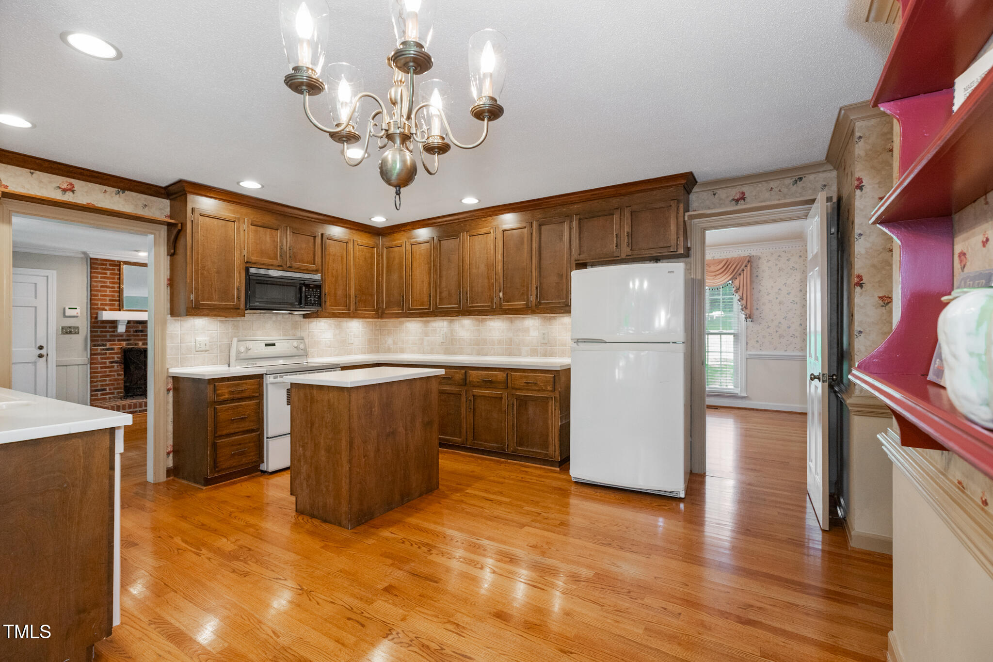 6904 Aspen Court Raleigh, NC 27615 - Photo 17 of 51 a kitchen with a refrigerator a sink dishwasher a stove and a dining table with wooden floor