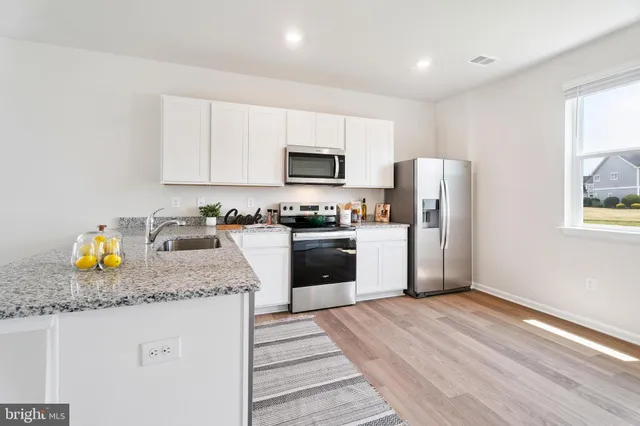 a kitchen with granite countertop white cabinets and stainless steel appliances