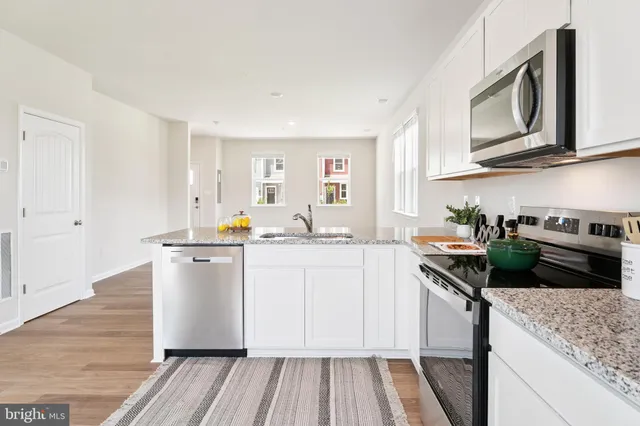 a kitchen with stainless steel appliances granite countertop a sink a stove a refrigerator a microwave and cabinets