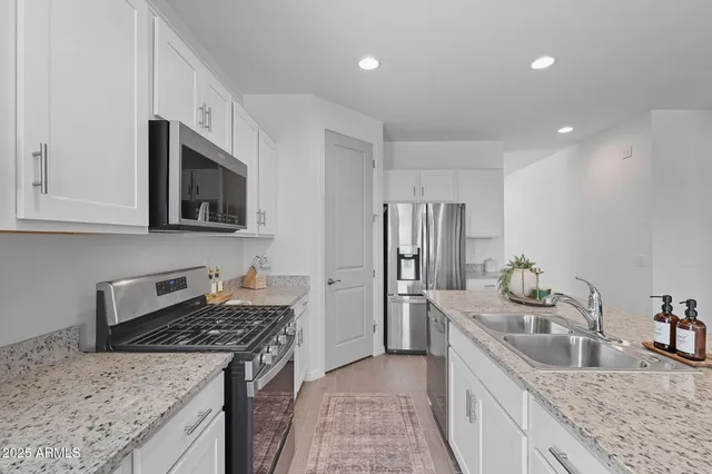 a kitchen with stainless steel appliances granite countertop a sink stove and refrigerator