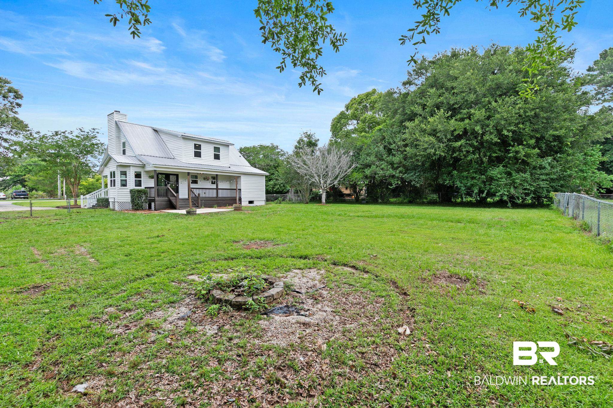 22810 High Ridge Road Fairhope, AL 36532 - Photo 54 of 78 Spacious green lawn surrounding the home, featuring a white exterior with a metal roof, dormer windows, and a covered porch with dark wood-finish decking