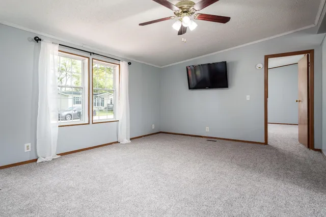 an empty room with windows and fan