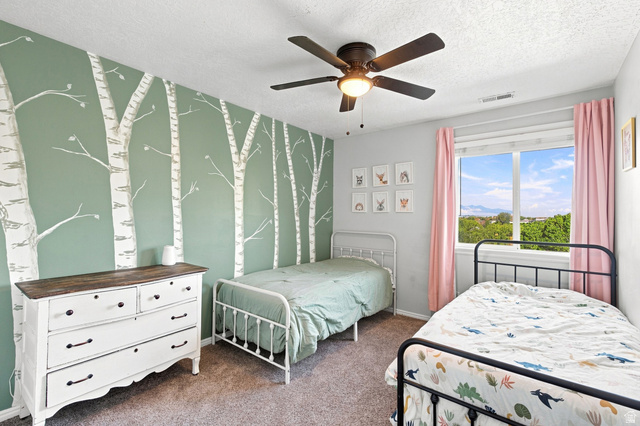 11882 Pond Ridge Drive Draper, UT 84020 - Photo 22 of 49 Accent wall with tree motif, ceiling fan with integrated lighting, window with mountain backdrop, neutral wall color, and carpeted flooring