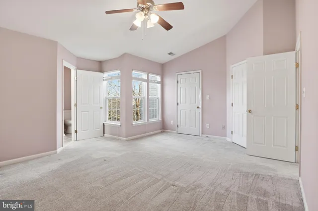 an empty room with chandelier fan and windows