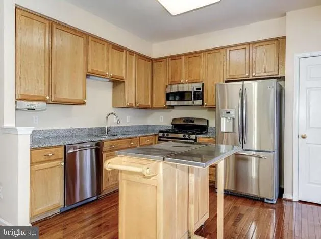 a kitchen with a refrigerator a stove a sink cabinets and wooden floor