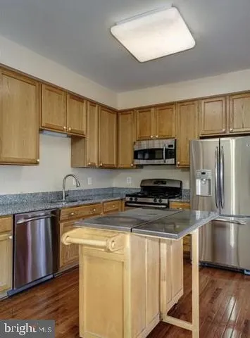 a kitchen with stainless steel appliances granite countertop a stove a sink dishwasher a refrigerator and a microwave