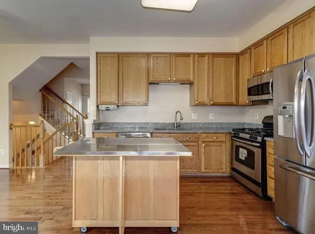 a kitchen with stainless steel appliances granite countertop a stove a sink and a refrigerator