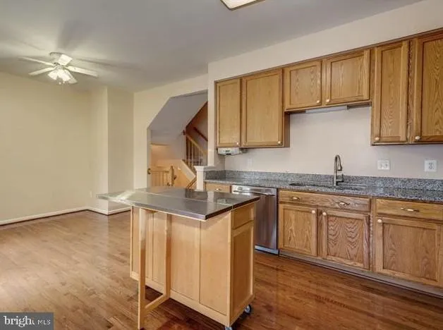 a kitchen with granite countertop a sink cabinets and wooden floor