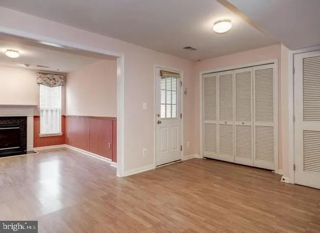 an empty room with wooden floor fireplace and windows