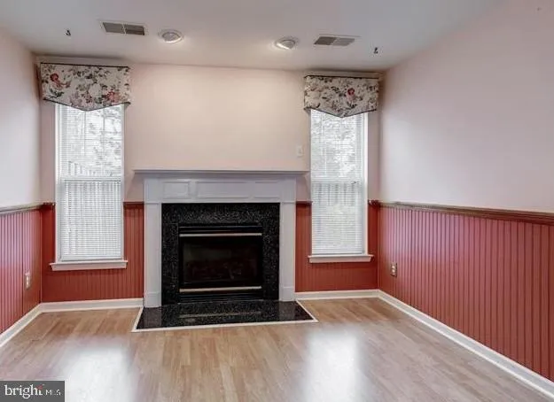 an empty room with wooden floor a fireplace and windows