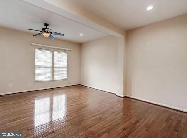 an empty room with wooden floor chandelier fan and windows