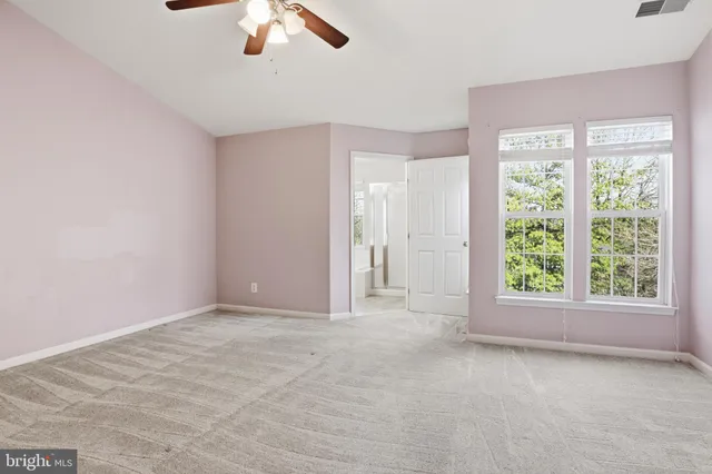 a view of an empty room with window chandelier fan