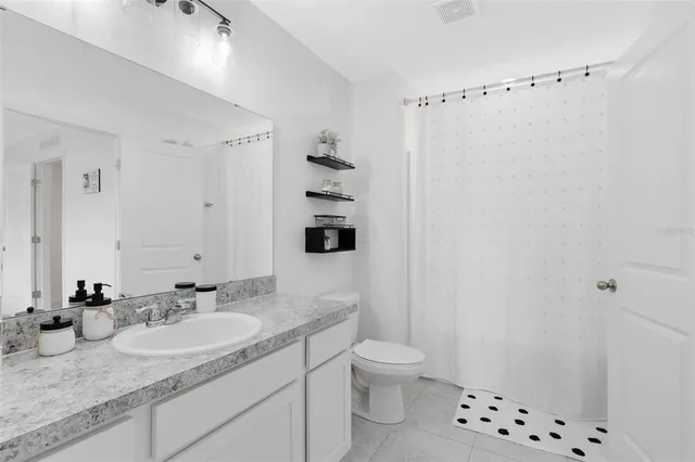 a bathroom with a granite countertop sink a toilet a shower and a mirror
