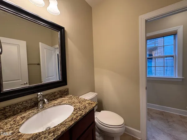 a bathroom with a granite countertop toilet a sink and mirror