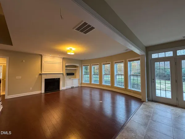 a view of an empty room with wooden floor and a fireplace