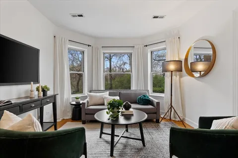 a living room with furniture a rug a window and a flat screen tv