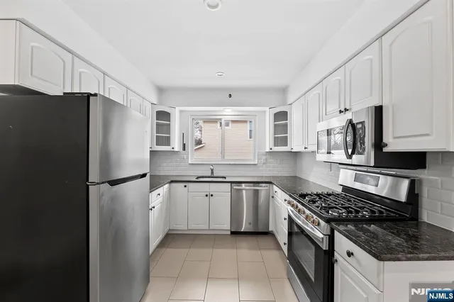 a kitchen with stainless steel appliances granite countertop a refrigerator stove and sink