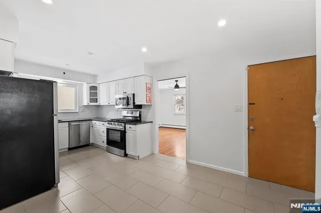 a kitchen with stainless steel appliances granite countertop a refrigerator a stove and a sink