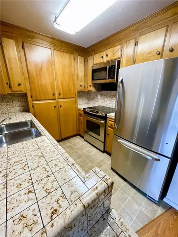 a kitchen with stainless steel appliances granite countertop a refrigerator sink and stove