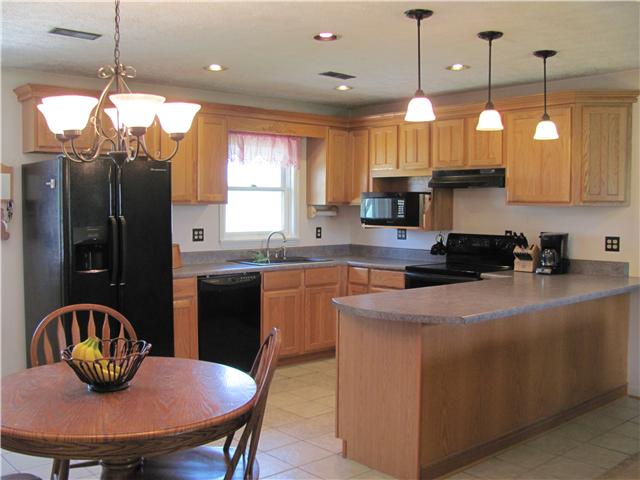 68 Pinegar Road Manchester, TN 37355 - Photo 3 of 15 The kitchen highlights the home's open living area. From beautiful cabinetry and lighting to a spacious countertop, eat-at/serving bar and tile flooring, this kitchen and eating area is the perfect place for family dinners and gatherings.