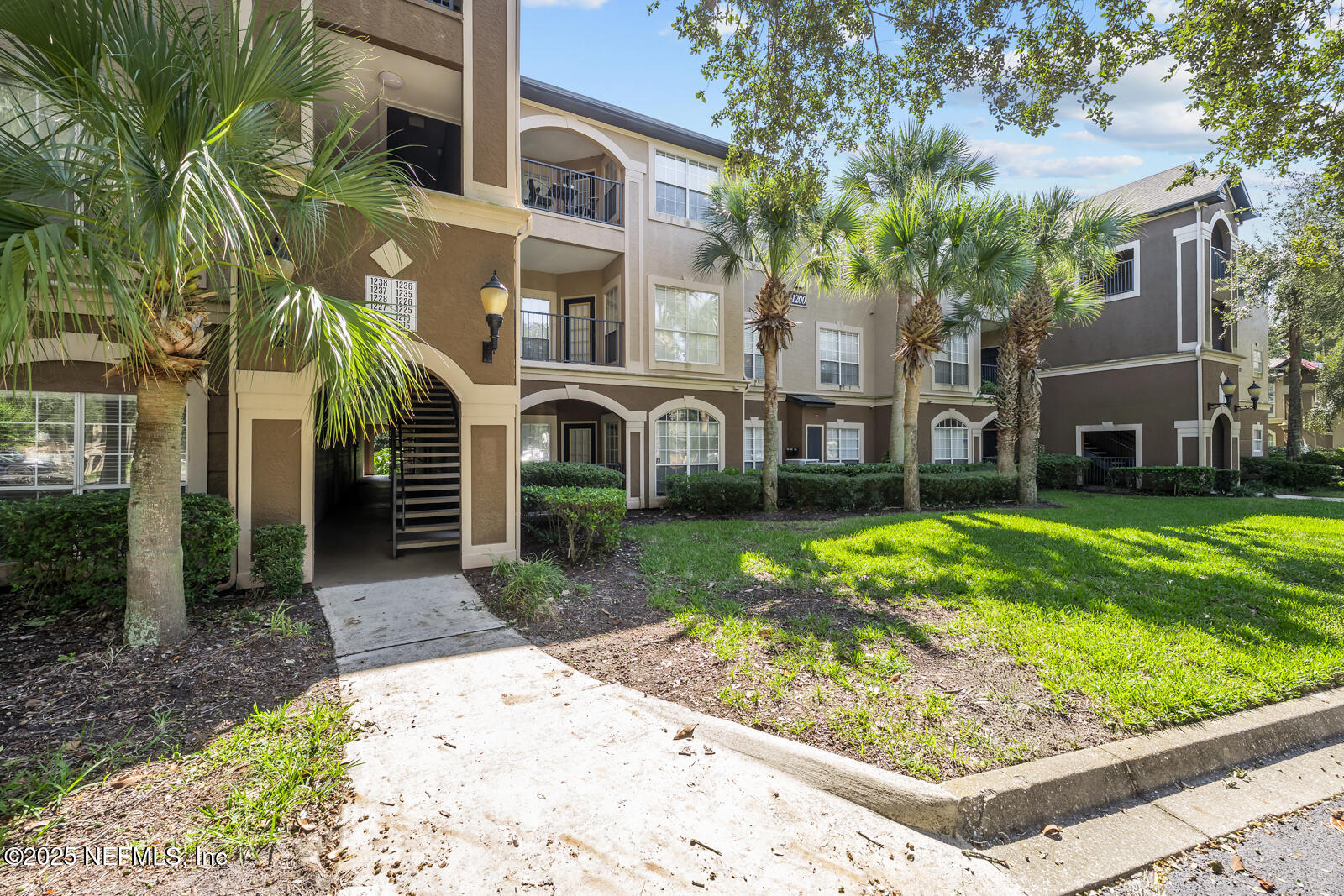 10961 Burnt Mill Road, Unit 1217 Jacksonville, FL 32256 - Photo 55 of 59 a view of a white house next to a yard with big trees