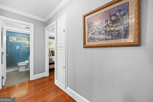 a view of a hallway with wooden floor and a bathroom