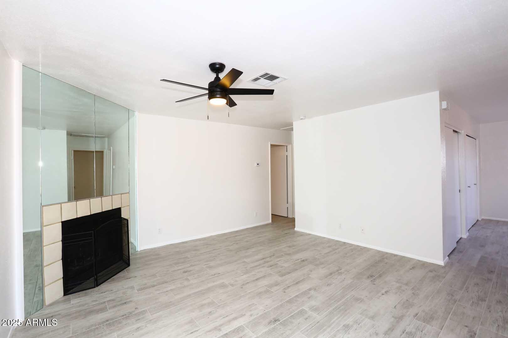 93 North Cooper Road, Unit 32 Chandler, AZ 85225 - Photo 11 of 33 a view of an empty room with wooden floor and a ceiling fan