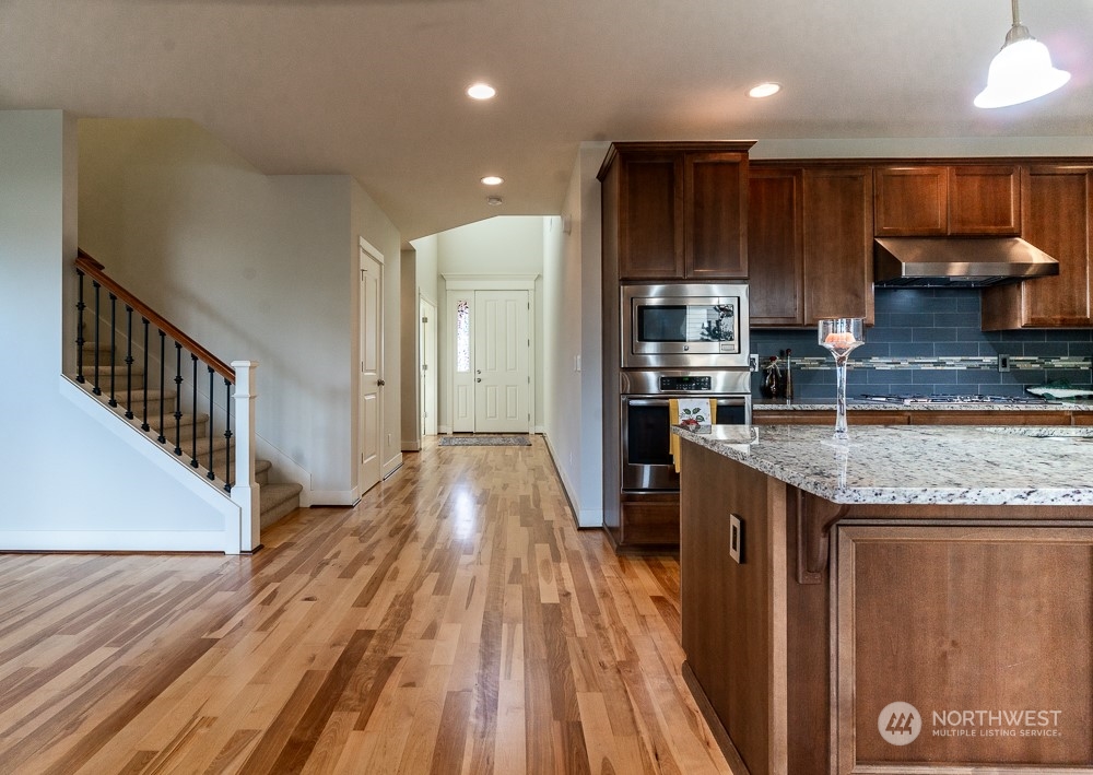 3825 221st Place Southeast Bothell, WA 98021 - Photo 23 of 40 a kitchen with granite countertop wooden floors wooden cabinets and stainless steel appliances